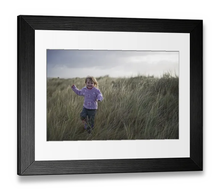 Framed Print : Young girl playing in sand dunes Waxham Norfolk winter