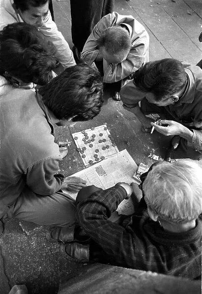 Men smoke and play a game of checkers in Canton, China