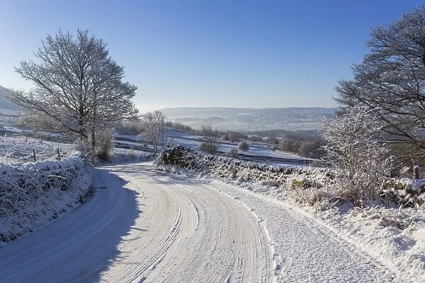 Snowy, bendy country lane with stone walls and trees, Curbar Edge, Peak District National Park, Derbyshire, England, United Kingdom, Europe