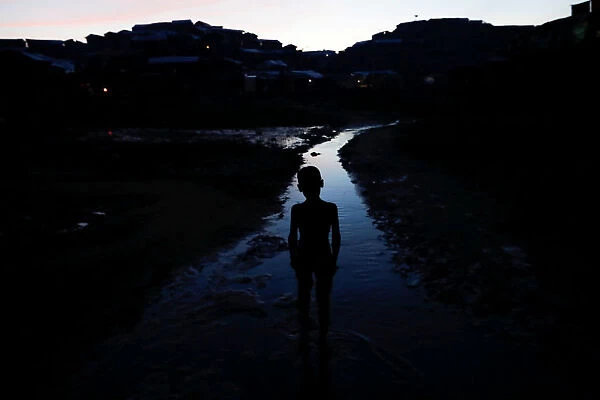 A Rohingya refugee boy walks in the water at a refugee camp near Coxs Bazar