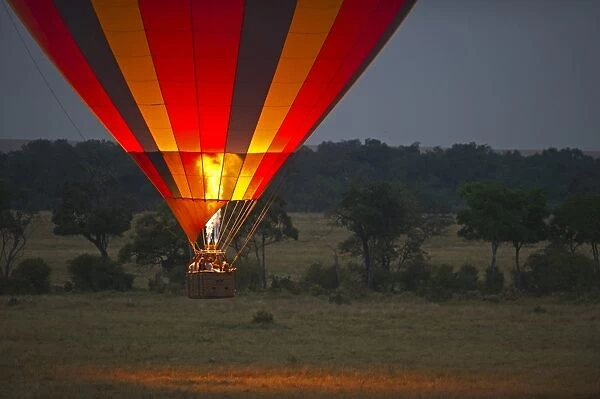 Hot air balloon carrying tourists over Masai Mara Kenya at dawn