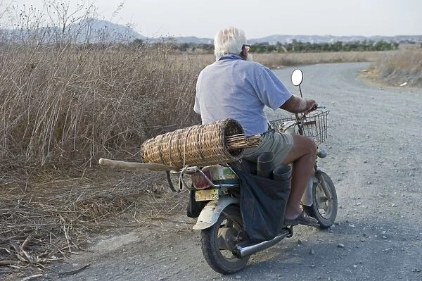Illegal trapper with limesticks on back of motorcycle going to orchard to set up