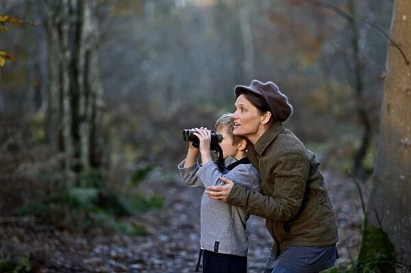 Mother showing son birds in woodland in autumn Norfolk
