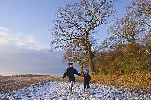 Mother and son walking in snow Norfolk December