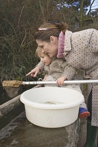 Mother and toddler pond dipping in spring UK