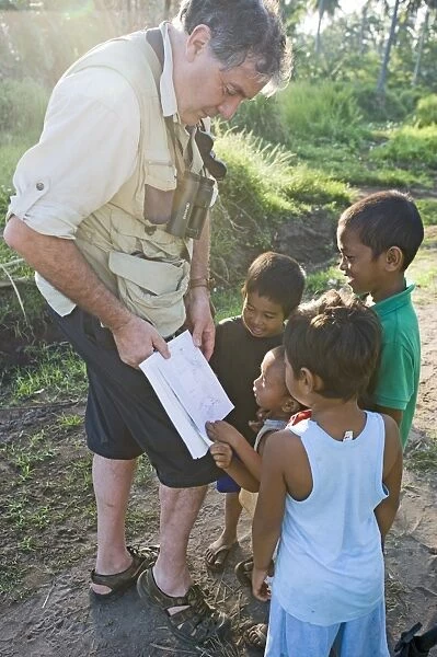 Tim Appleton showing local boys bird illustrations in a field guide at Narra on Palawan