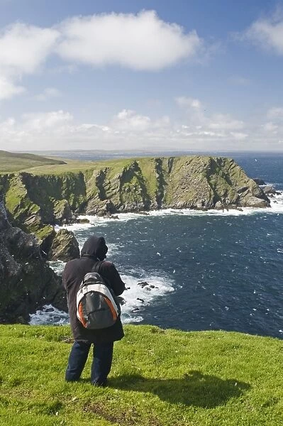 walker looking out across sea cliffs at Hermaness NNR on Unst Shetland June