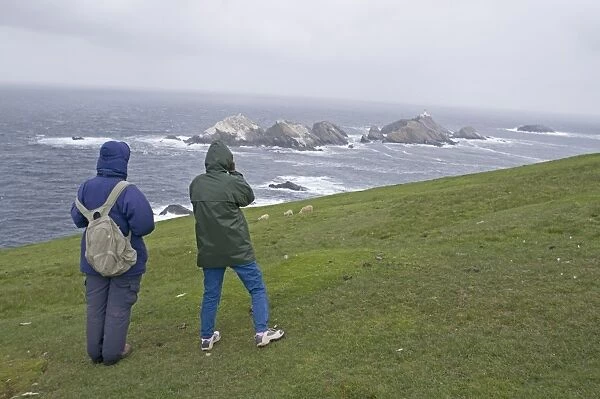 Walkers looking out on Britains most northerly point Muckle Flugga off Hermaness