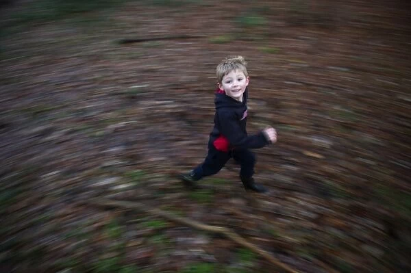 Young boy playing in woodland in winter Norfolk December