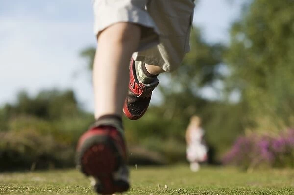 Young boy running on heath exploring nature Norfolk summer