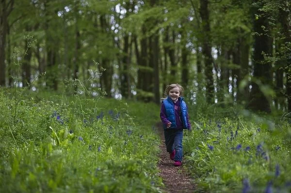 Young girl running along woodland path Norfolk May