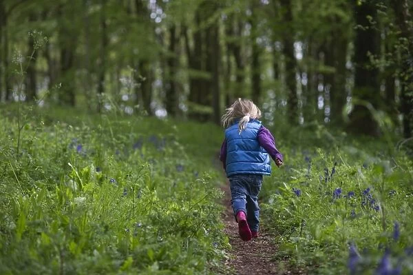 Young girl running along woodland path Norfolk May