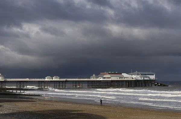 View of beach and pier of seaside town, with stormclouds overhead, Cromer Pier, Cromer, Norfolk, England, november