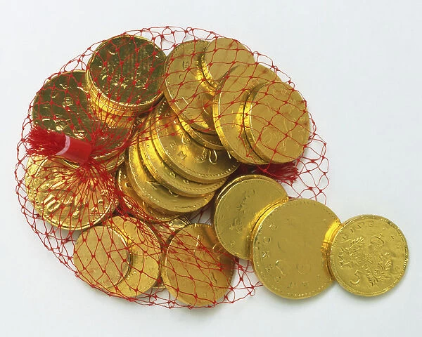Gold foil-wrapped chocolate coins in a red net bag, close up