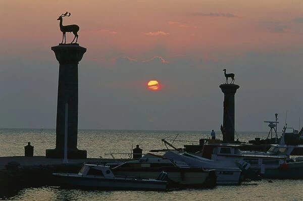 Greece, Rhodes, deer statues of Elafos and Elafina stand atop columns above boats moored in Mandraki harbour