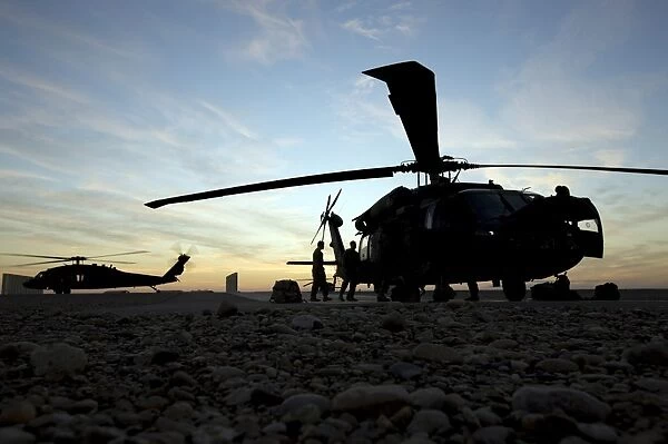 A UH-60 Black Hawk helicopter on the flight line at sunset