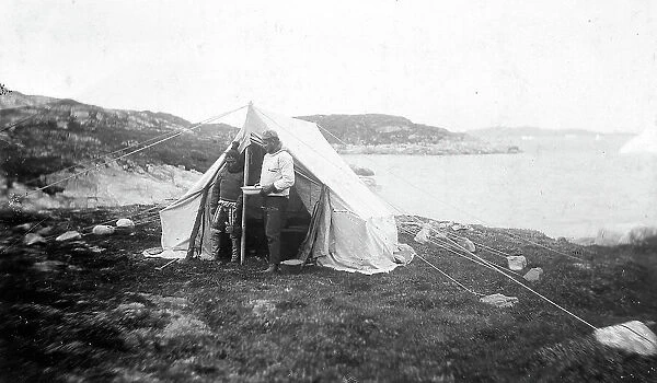 Portrait of an explorer together with a South-American woman, during the expedition to the Tierra del Fuego. They pose standing up in front of a tent
