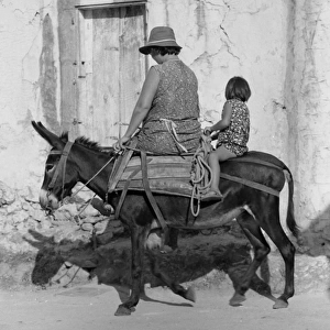 Woman and girl riding a small donkey