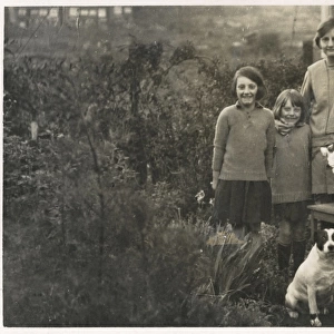 Woman and four girls with a dog in a garden