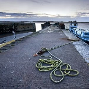 Beadnell Harbour at dusk showing old rope coiled on harbourside and dilapidated fishing boat