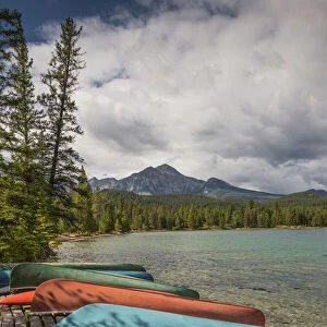 Colourful canoes and kayaks on the bank of Annette Lake with Pyramid Mountain in the background
