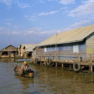 Man in canoe passing a house, floating fishing village of Chong Kneas, Tonle Sap lake