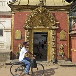 Man cycling past the Golden Gate, Sun Dhoka, in Durbar Square, Bhaktapur