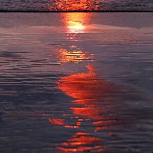 Sunset reflection on wet sand on Legian Beach, Denpasar, Bali, Indonesia