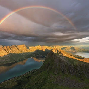 A complete rainbow above the fjords of Senja Island on a rainy summer evening. Norway