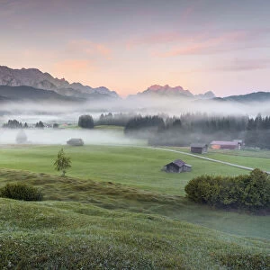 humped meadows with wafts of mist at sunrise and Karwendel Range and Zugspitz-Massif