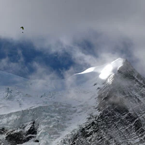 A paraglider flies above the Bossons glacier in the Mont-Blanc massif on a sunny autumn