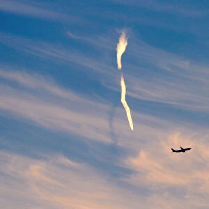 The trail of an aeroplane can be seen amongst clouds and above a plane after it took