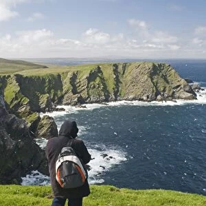 walker looking out across sea cliffs at Hermaness NNR on Unst Shetland June