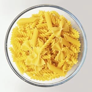 Bowl of mixed dry pasta, including fusilli, farfalle and penne, view from above