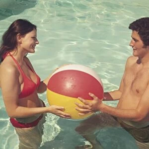 Couple playing with a ball in the pool