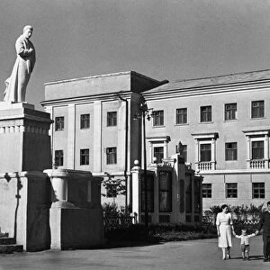 A family strolling under the benificent gaze of a sculpture of josef stalin, the great continuer of lenins cause on one of the central thoroughfares of stalinogorsk, in the moscow coal basin, ussr, 1950