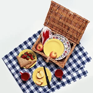 Wicker picnic hamper filled with sandwiches, fruit, plates and cutlery