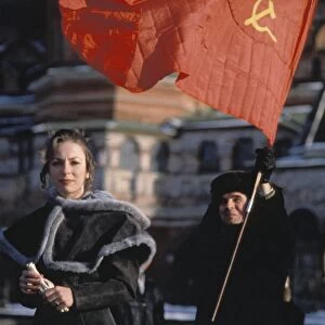 A young woman with a man carrying a soviet hammer and sickle flag during an anti-government demonstration in red square, early 1990s