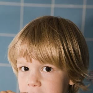 Four-year-old blond boy brushing his teeth