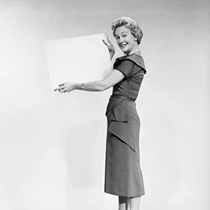 Woman holding blank piece of paper, portrait, studio shot