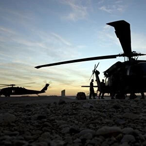 A UH-60 Black Hawk helicopter on the flight line at sunset