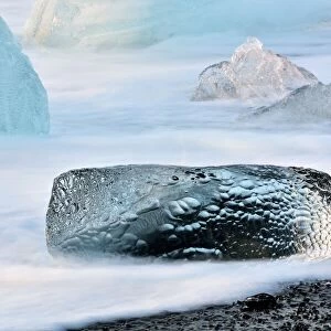 Long exposure image of crystal clear iceberg formations on the volcanic beach, Jokulsarlon, Iceland
