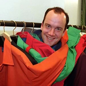 Jack Docherty TV Presenter in between clothes rail full of coloured jackets