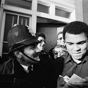 A policeman smiles at Muhammad Ali as he signs autographs in London