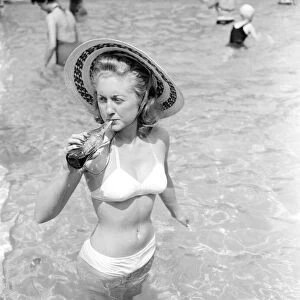 Woman bather cools down with a bottle of Coca Cola at the local lido. August 1952