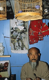 Bird trader in Beijing bird market China 1993. Siberian Rubythroat in cage hanging from ceiling Bird trader in Beijing bird market China 1993. Siberian Rubythroat in cage hanging from ceiling