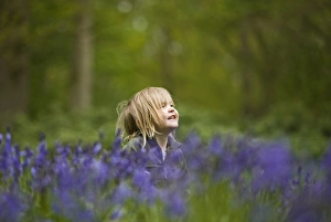 Child playing among Bluebells Norfolk May