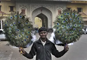 Tourist Prints: Hawker with decorative peacock feather fans being sold to tourists in Jaipur India