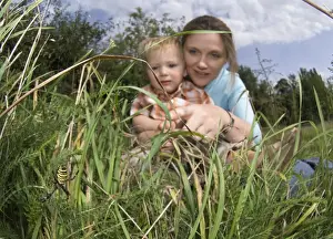 Garden Urban Prints: mother and 2yr old son looking at Wasp Spider in garden Kent UK summer
