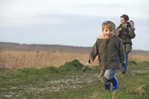 mother carrying toddler in backpack while bird watching along coastal path North